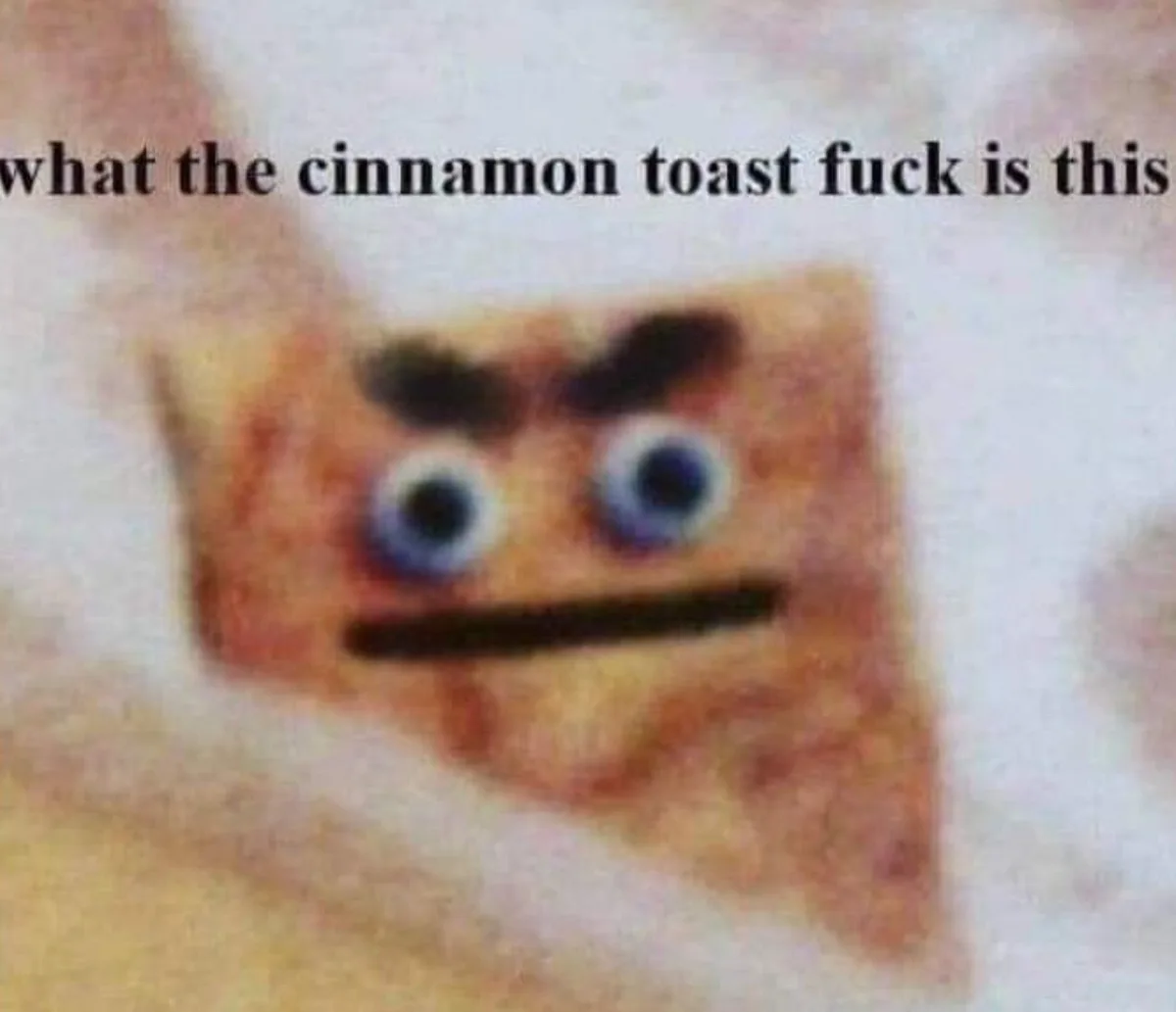 A blurry, low-resolution image of a square-shaped, brownish object with cartoonish blue eyes, dark eyebrows, and a straight…