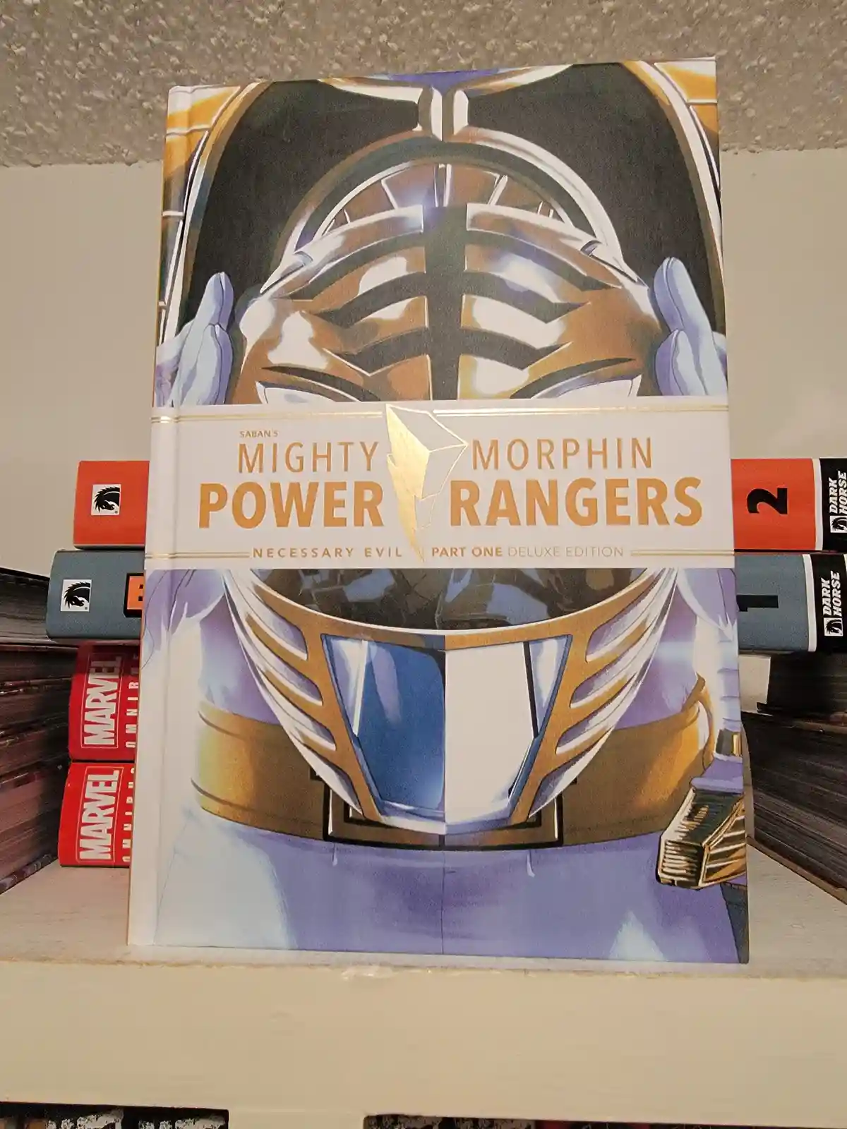 A close-up photo of a 'Saban's Mighty Morphin Power Rangers: Necessary Evil Part One Deluxe Edition' comic book standing…