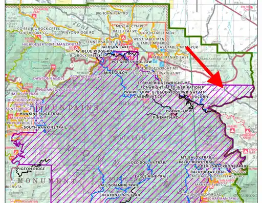 A topographic map of a mountainous region with trails and roads, overlaid with a large red arrow pointing to a specific area…