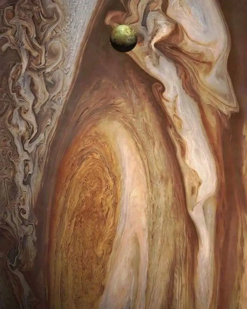 a close-up image of jupiter's swirling clouds in shades of brown, beige, and white, with a small greenish moon, io…
