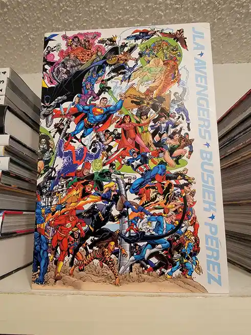 A comic book cover featuring a dense, chaotic collage of numerous superheroes from both DC and Marvel universes, including…