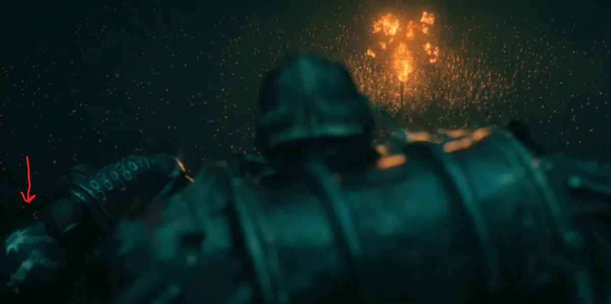 A blurry, dark image shows a person in heavy armor lying on their back, with a red arrow pointing to their left hand. Behind…