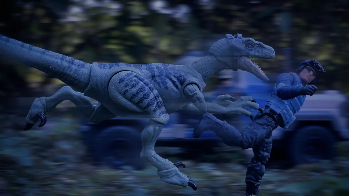 A blue velociraptor action figure is shown running alongside a human action figure in tactical gear, both in motion with a…