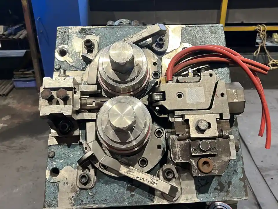 A close-up photo of a complex, worn industrial machine with metal components, bolts, and red cables, overlaid with the text…