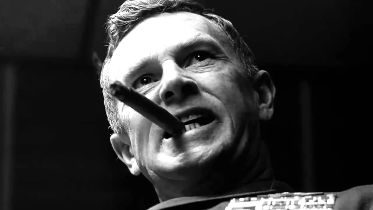 A black-and-white close-up of a man with a cigar in his mouth, looking upward with a slightly amused or resigned expression…