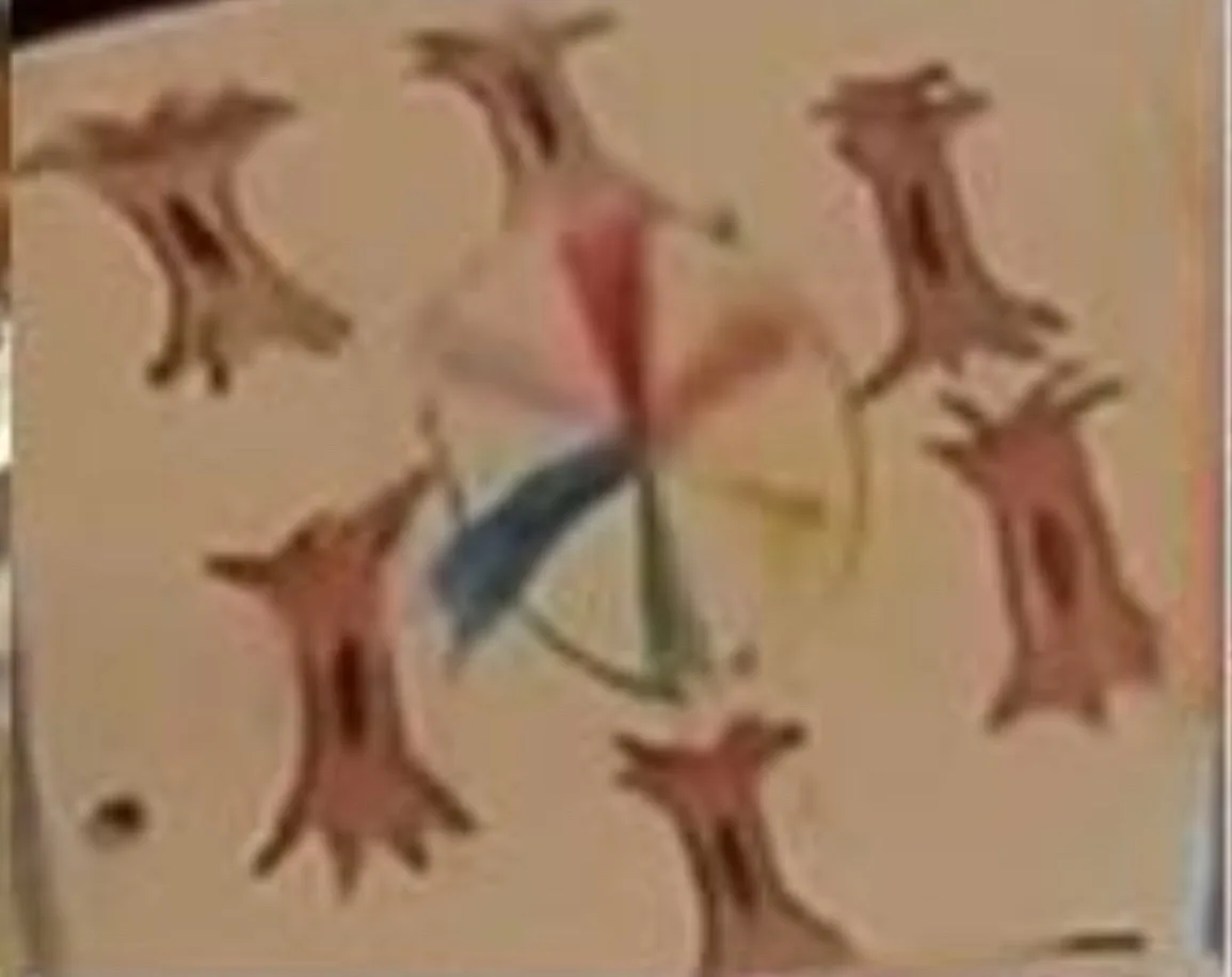 A blurry image shows a colorful spinning wheel with six abstract, brown, tree-like or creature-like figures arranged around…