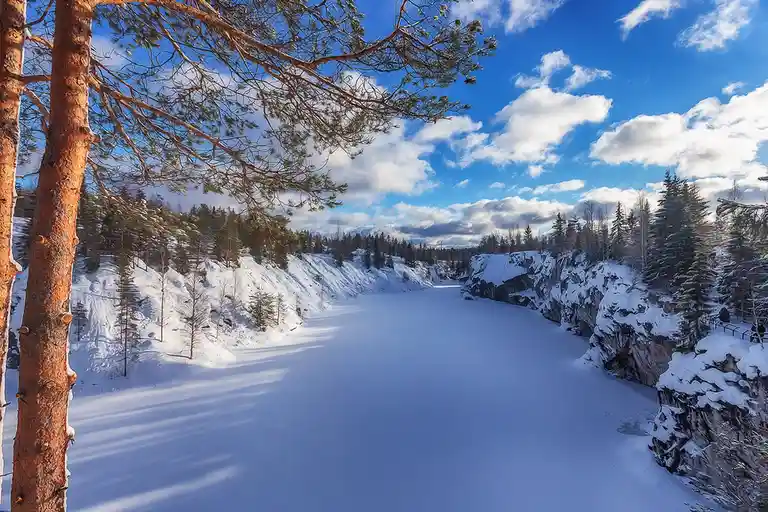 A serene winter landscape shows a wide, snow-covered frozen lake flanked by snow-dusted cliffs and evergreen trees under a…