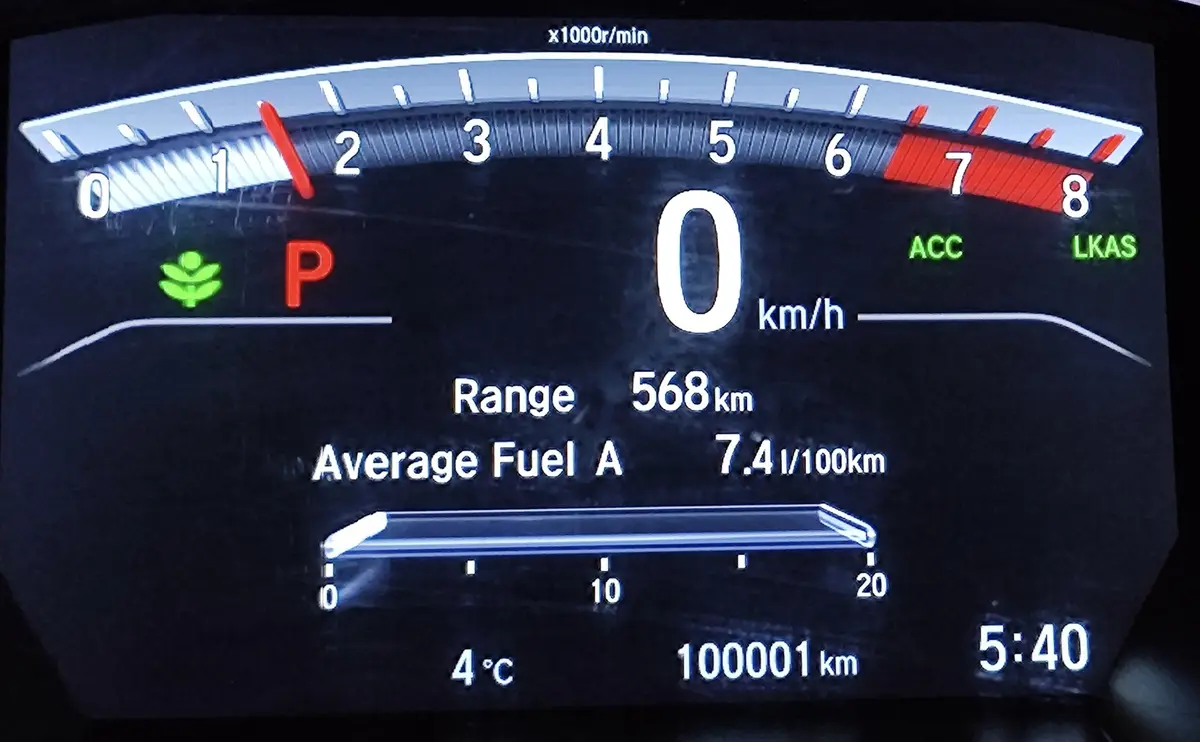 A car's digital dashboard shows the odometer reading '100001 km' while the speed is 0 km/h, the engine is idling at 1,200…