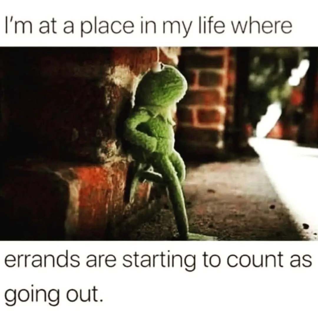A green Kermit the Frog plush toy is shown leaning against a brick wall in a dimly lit alleyway, appearing dejected or…