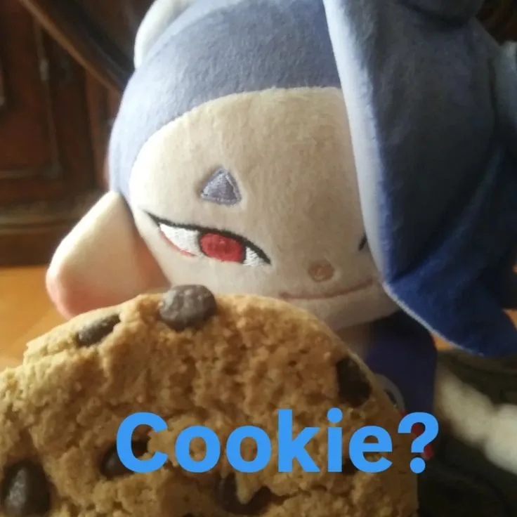 A plush toy of the character Milla from Monster Hunter Rise is shown with a mischievous, slightly suspicious expression…