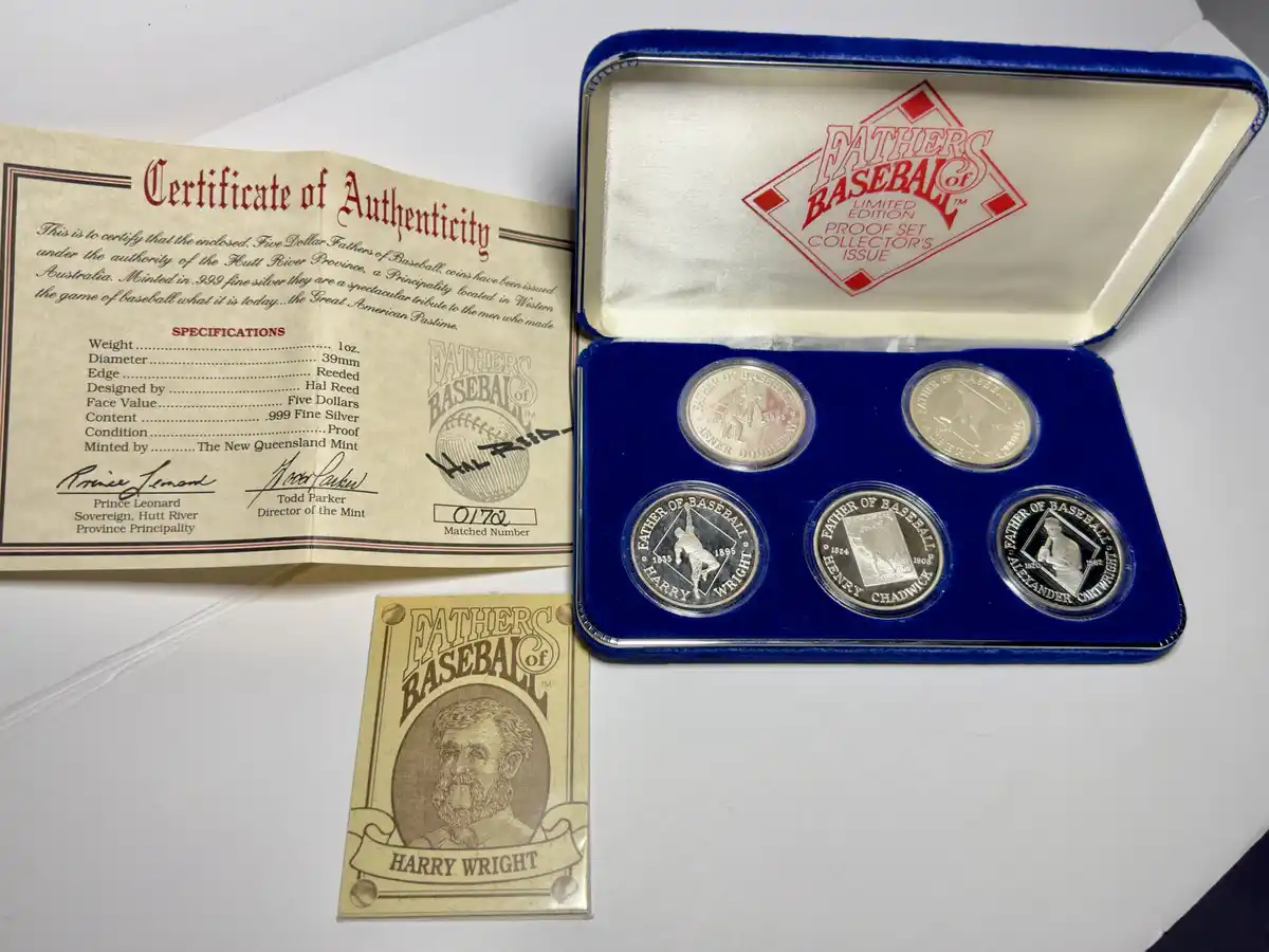 A collector's set of five silver coins titled 'Fathers of Baseball' is displayed in a blue velvet case, accompanied by a…