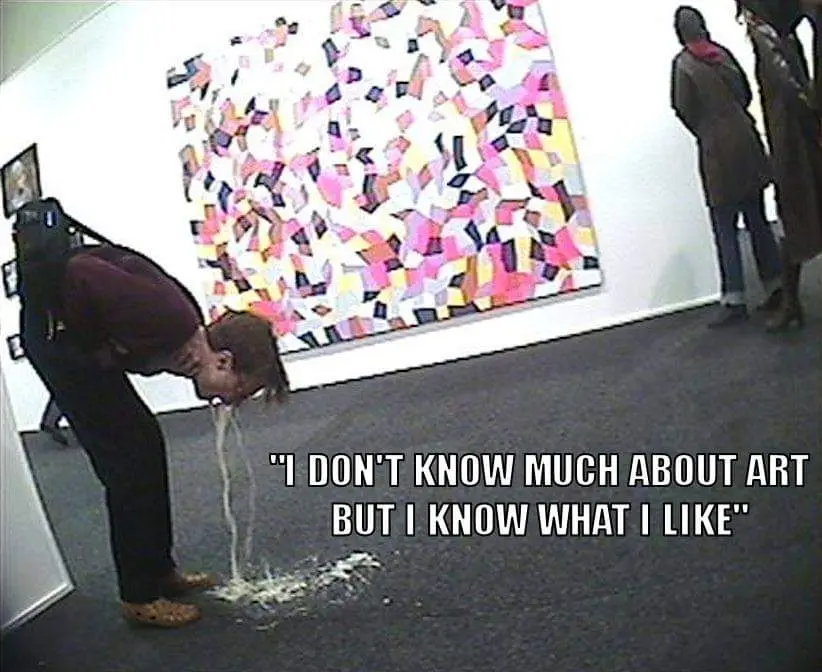 A person in a maroon shirt and black pants is bent over, spitting a stream of liquid onto the floor in front of a colorful…