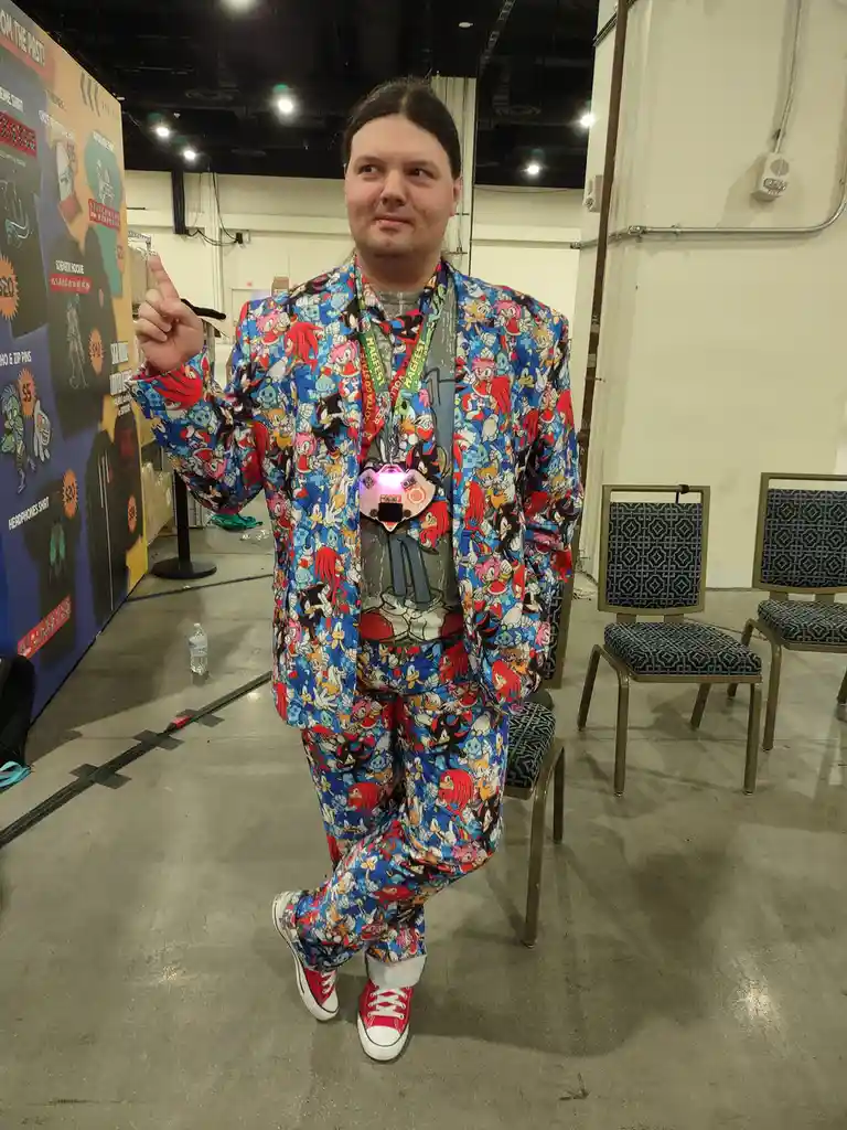A person wearing a full Sonic the Hedgehog-themed suit with repeating character prints, red sneakers, and a glowing…
