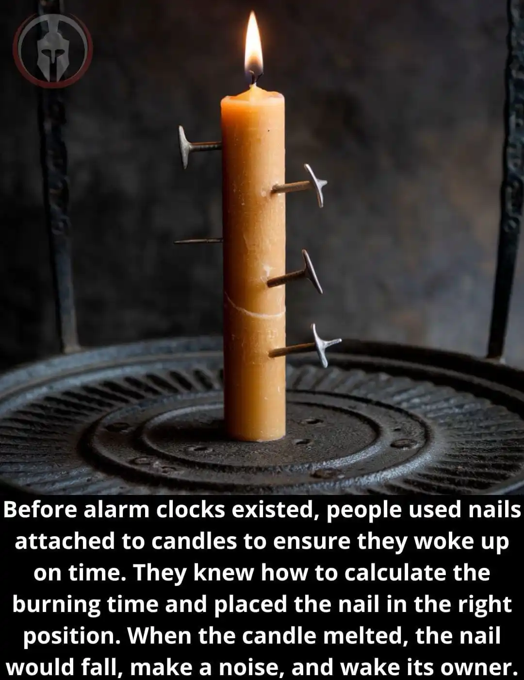 A lit candle with several nails stuck vertically into its sides sits on a dark metal surface. The overlaid text explains…