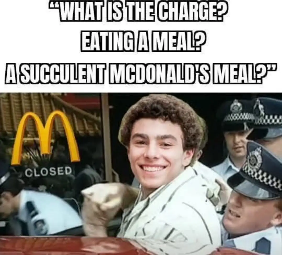 A man with curly hair smiles confidently while being escorted by police officers, with a McDonald's sign visible in the…
