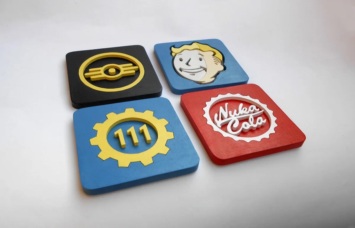 Four square wooden coasters arranged in a diamond pattern on a white surface, each featuring a raised logo: top-left is the…