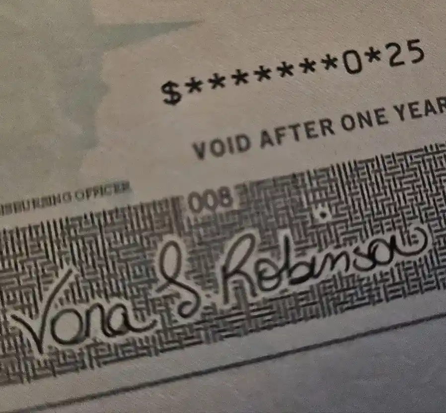A close-up of a check with the amount obscured by asterisks, showing '$*******0*25' and the text 'VOID AFTER ONE YEAR'…