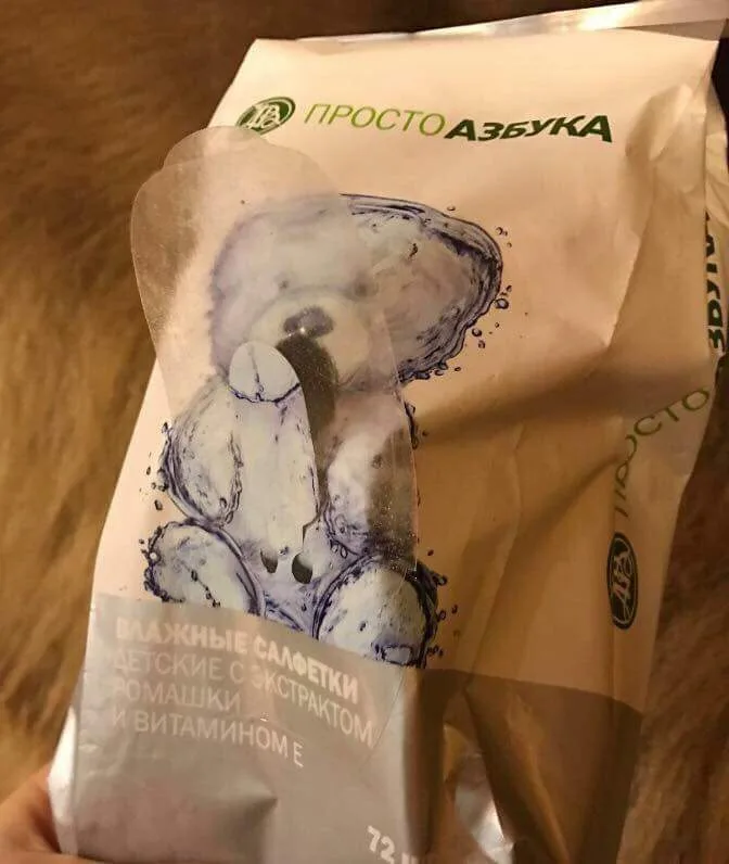 A close-up photo of a crumpled white paper package of 'Просто Азбука' brand baby wipes, featuring a blue watercolor-style…