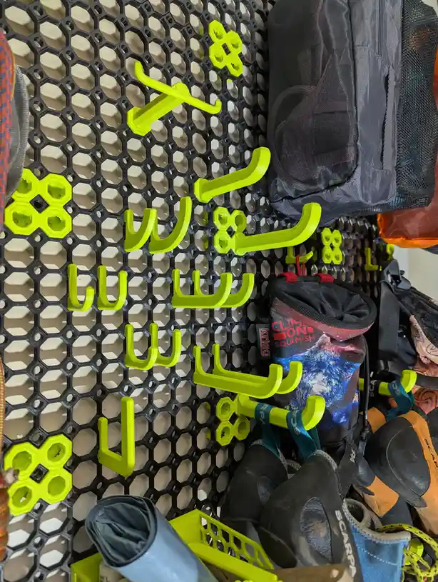 A close-up of a black hexagonal grid wall with bright lime green hooks arranged to spell out 'i'm not lazy, i'm just resting…