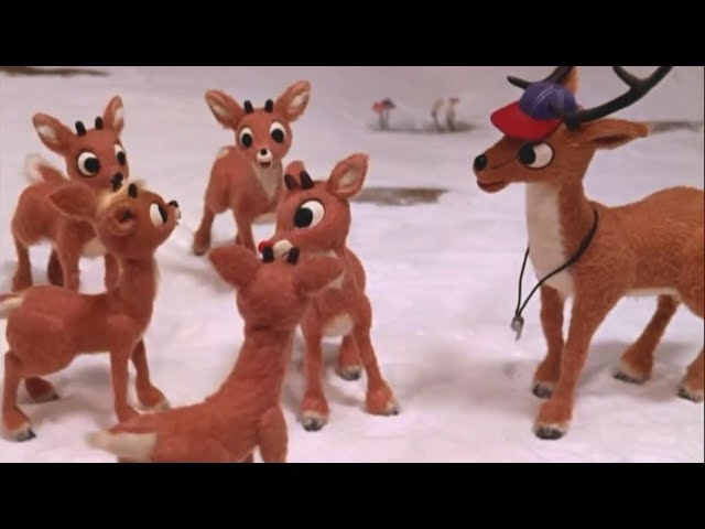 a still from the movie 'rudolph the red-nosed reindeer' shows rudolph, wearing a red baseball cap and a black lanyard…
