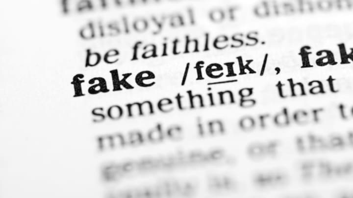 A close-up photo of a dictionary page showing the definition of 'fake' with the word 'fake' and its phonetic pronunciation…