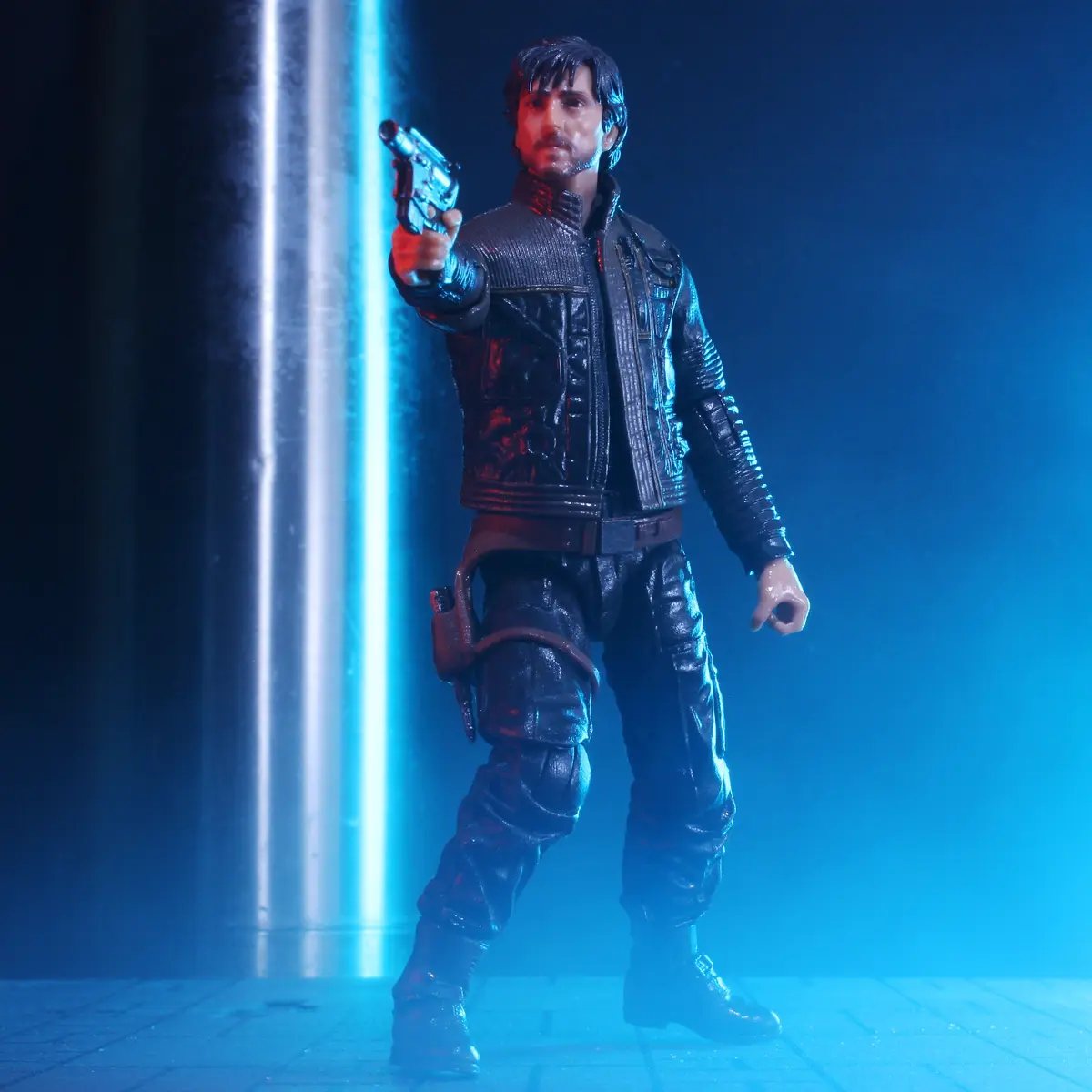 A Star Wars action figure of the character Kanan Jarrus stands in a dramatic pose, holding a blaster pistol pointed forward…