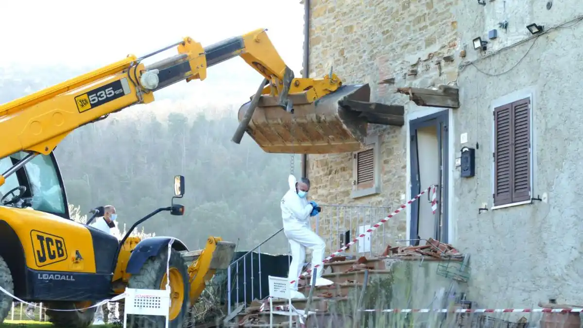 A yellow JCB Loadall telehandler with its bucket raised is positioned next to a stone building, appearing to demolish part…