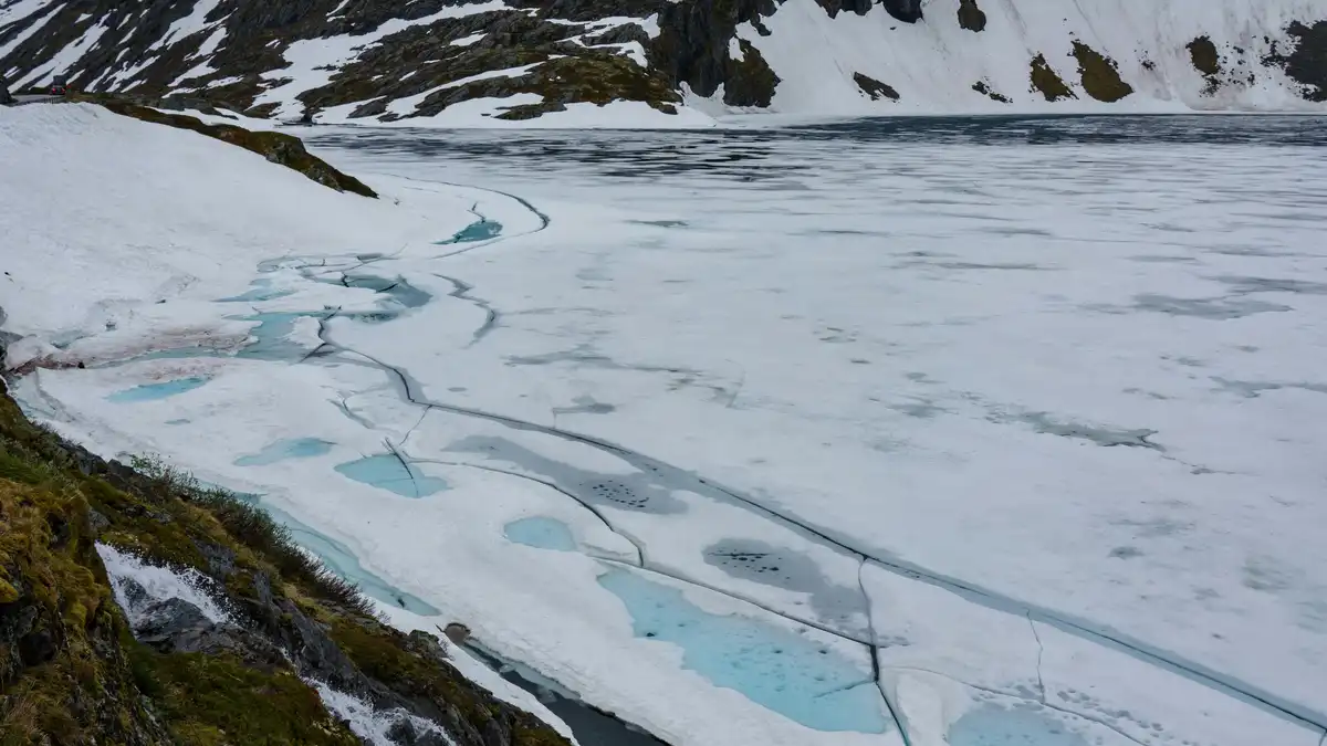 Frosty peaks stretch towards the sky, cloaked in a blanket of shimmering white. The frozen river below, a glassy expanse of…