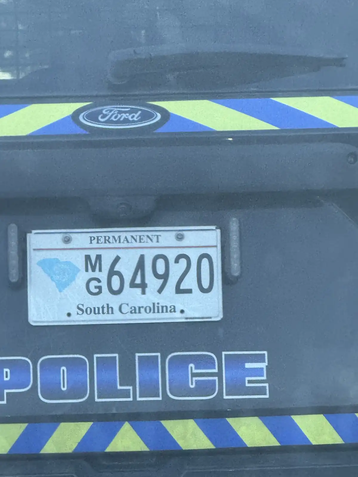 A close-up of the rear of a police vehicle showing a South Carolina license plate with the number M64920, which is…
