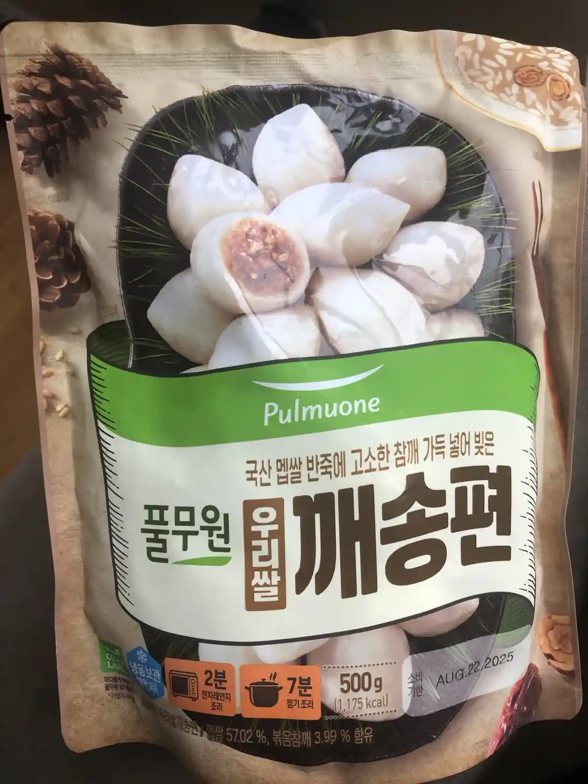 A close-up of a Korean food package for Pulmuone brand 'Our Rice' sesame rice cakes (깨송편), showing white dumpling-like…