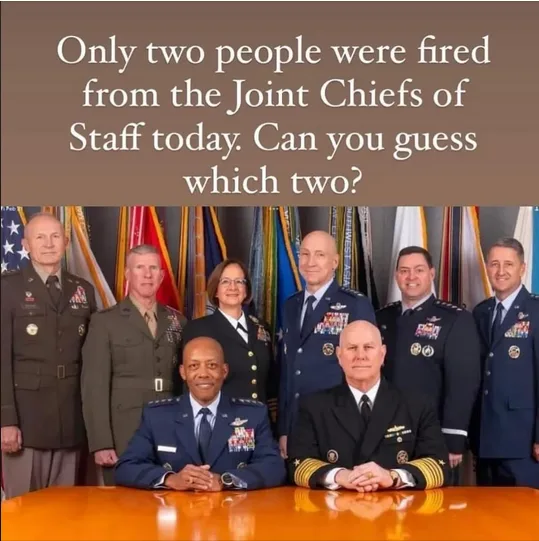 A formal group photo of seven military officers in uniform, standing and sitting behind a polished wooden table, with…