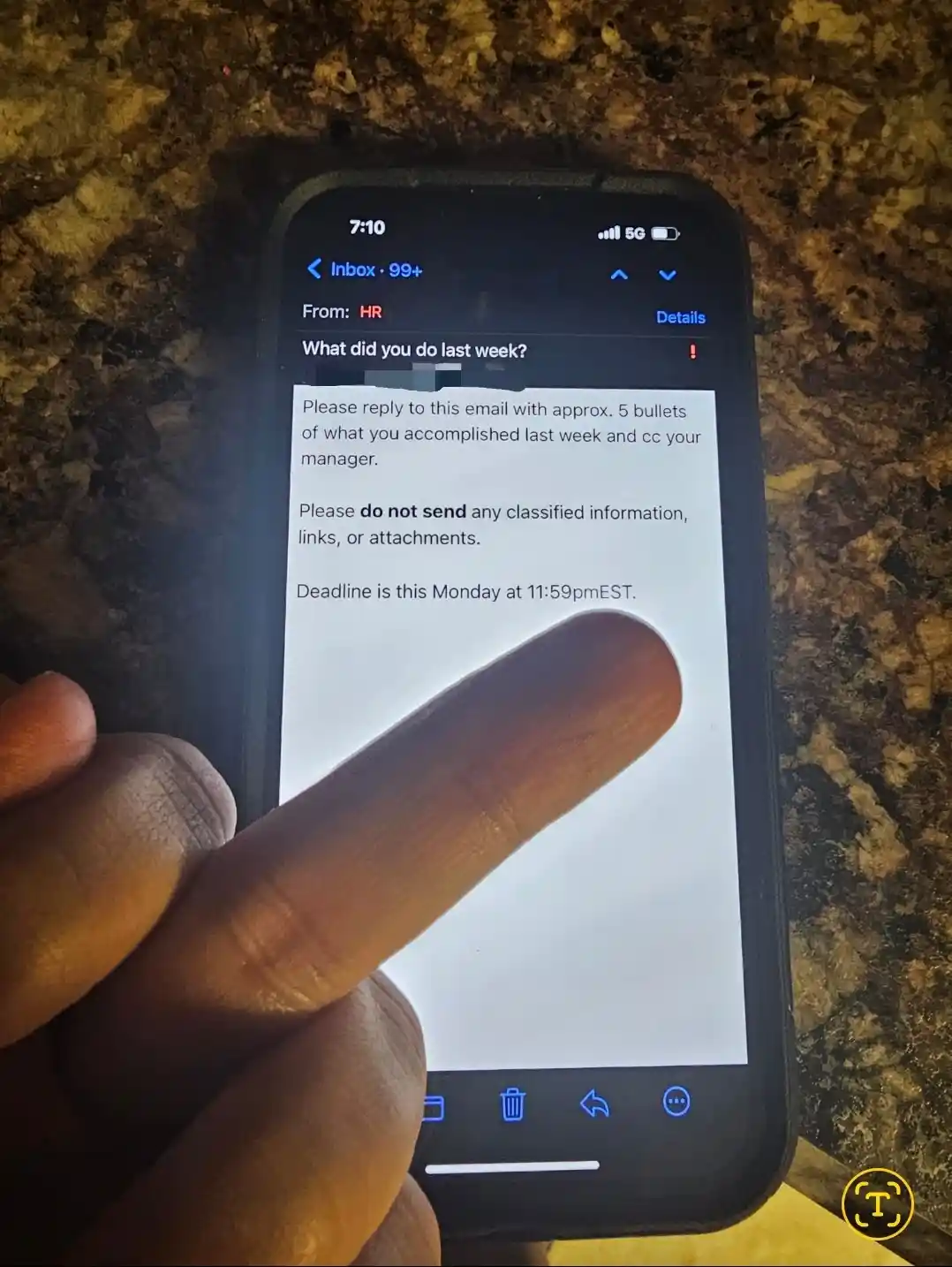 A close-up photo shows a person's finger pointing at a smartphone screen displaying an email from HR. The email asks the…