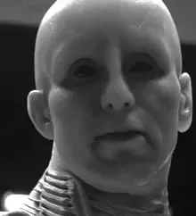 Six black-and-white stills show a bald, pale-faced character with a neck collar, progressing from a neutral expression to a…
