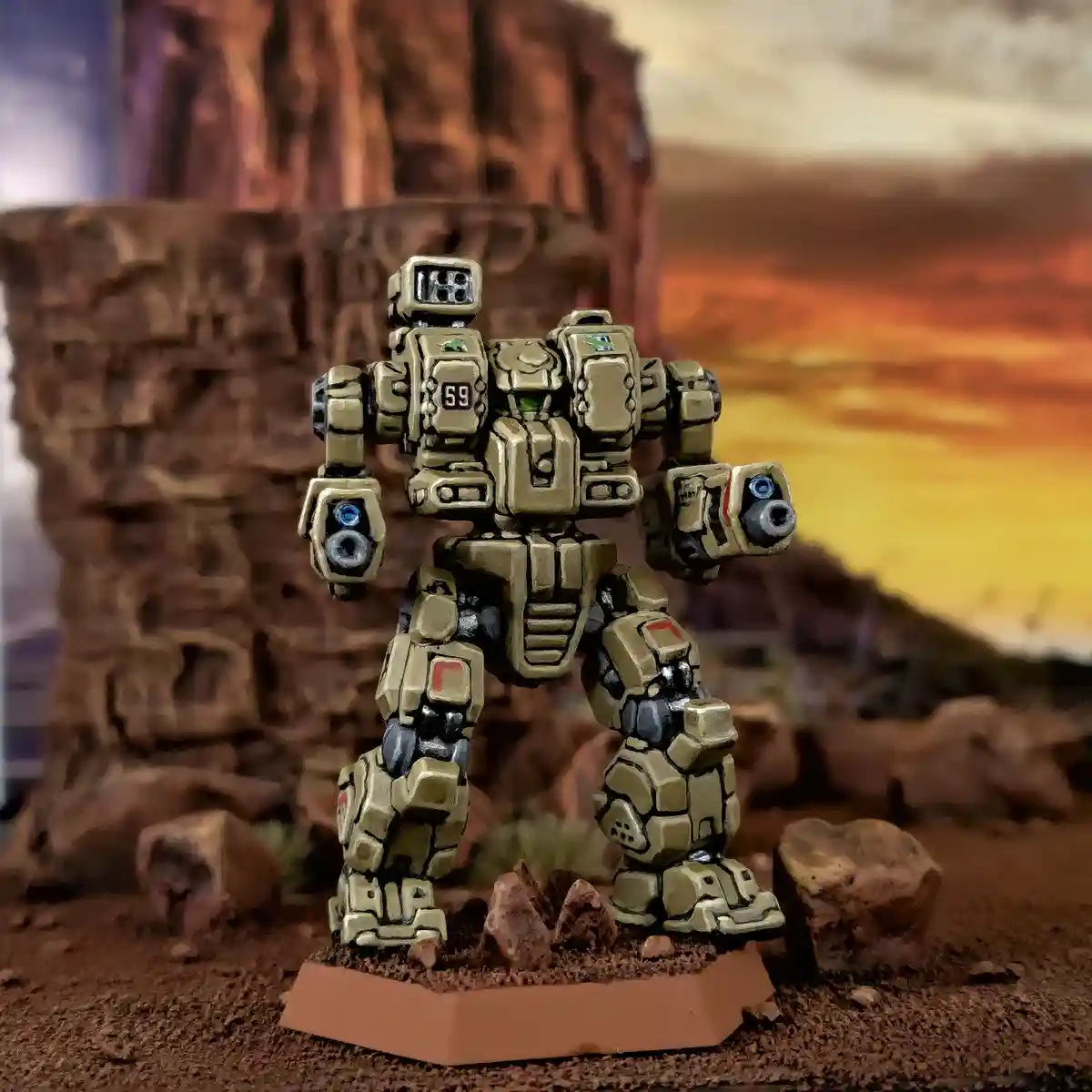 A painted miniature of a tan-colored humanoid robot stands on a hexagonal base in a desert diorama with rocky terrain and a…