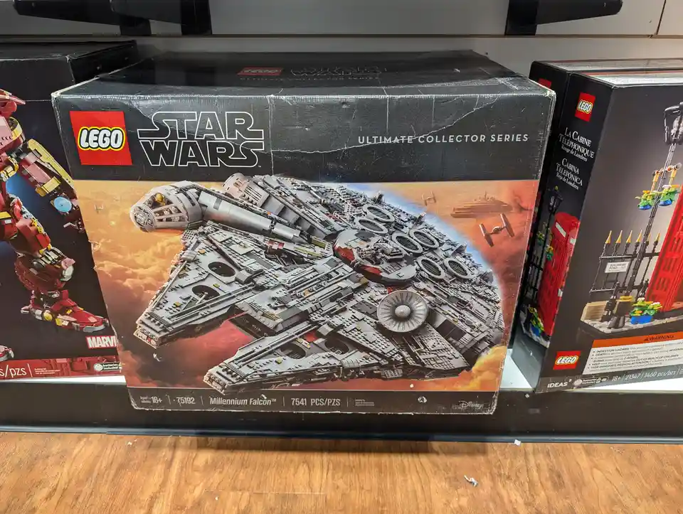 A close-up photo of a worn LEGO Star Wars Ultimate Collector Series Millennium Falcon box (set 75192) sitting on a store…