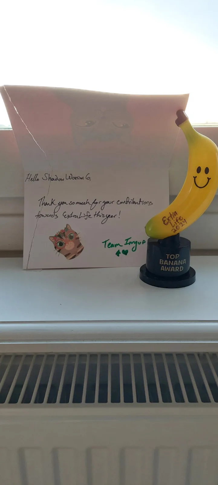 A handwritten note addressed to 'Shadow Warrior 6' thanking them for contributions to 'Extra Life 2024' sits next to a small…