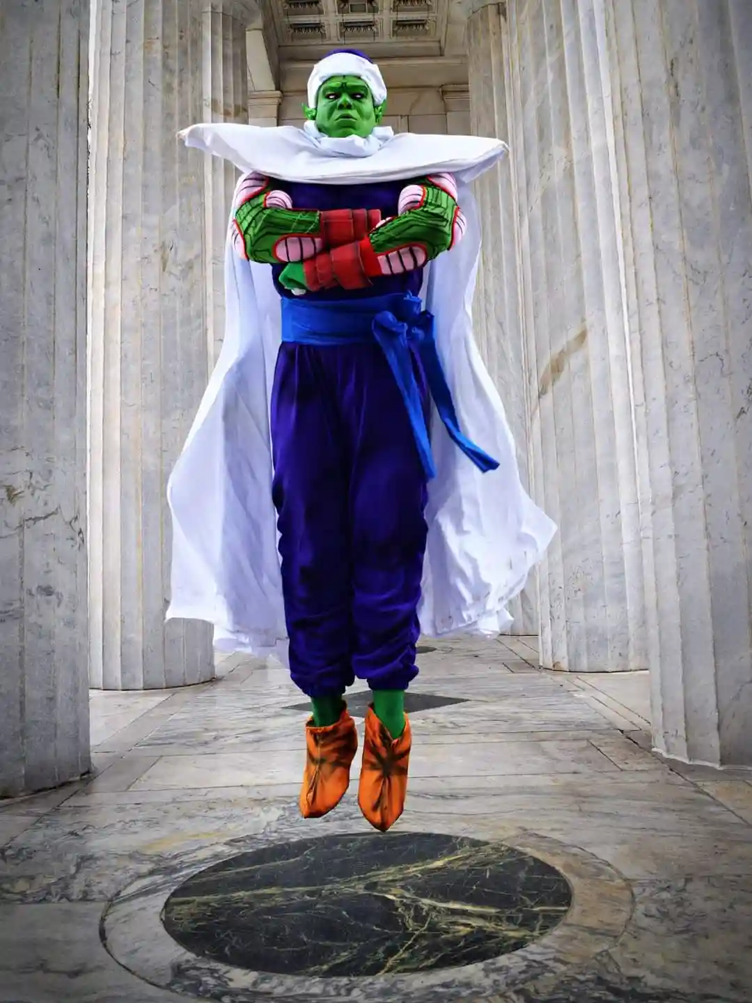 A person in a detailed green-skinned, white-caped, purple-outfit costume resembling the Dragon Ball character Piccolo is…