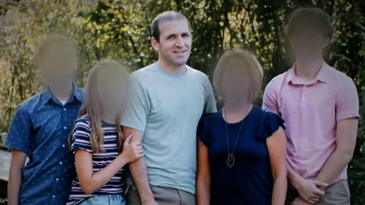 A family photo shows five people standing together outdoors with trees in the background. The faces of four individuals are…
