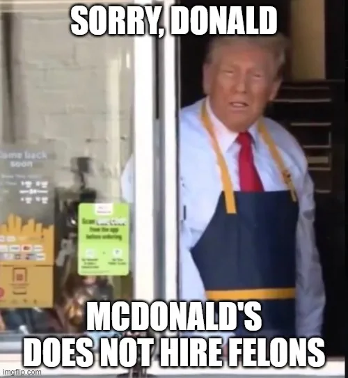 A man resembling Donald Trump, wearing a blue McDonald's apron with yellow straps over a white shirt and red tie, stands in…
