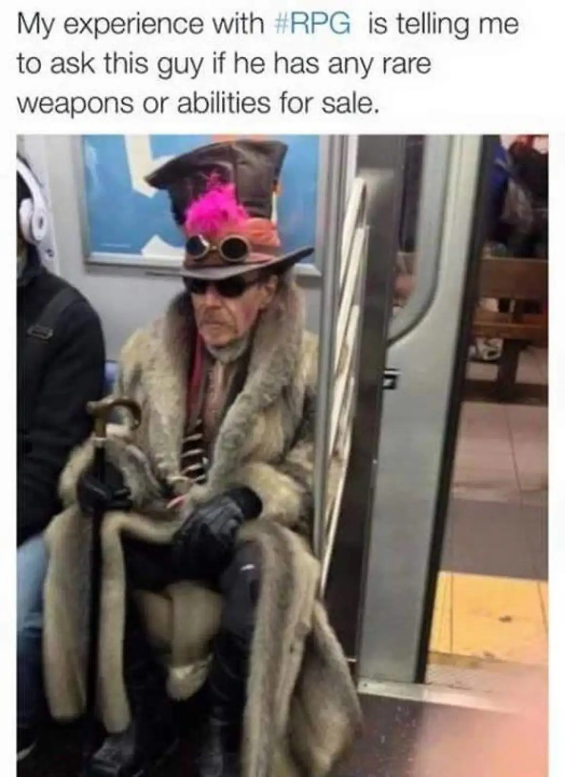 A man sits on a subway train wearing an elaborate costume including a tall hat with pink feathers, goggles, sunglasses, a…