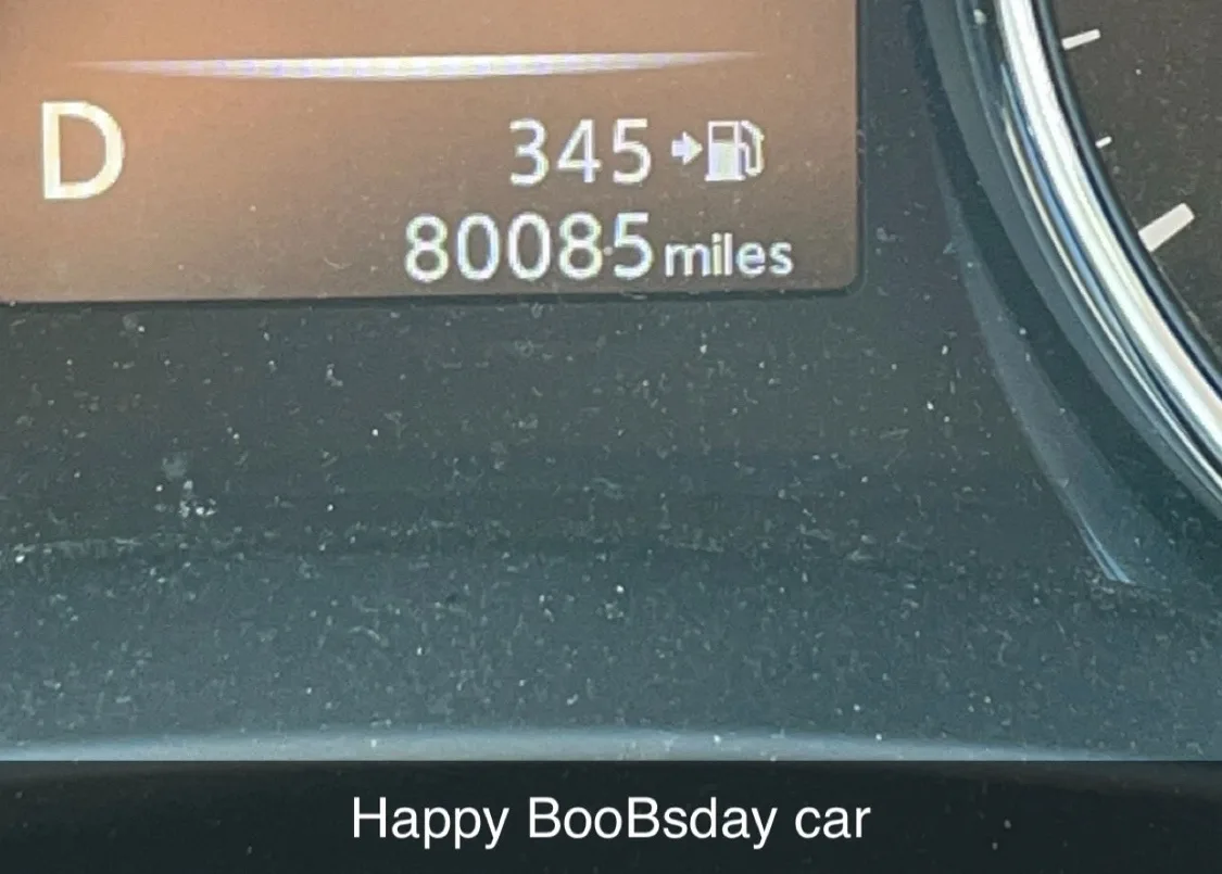 A close-up of a car's digital dashboard showing the odometer reading 80085 miles and fuel range 345 miles, with overlaid…