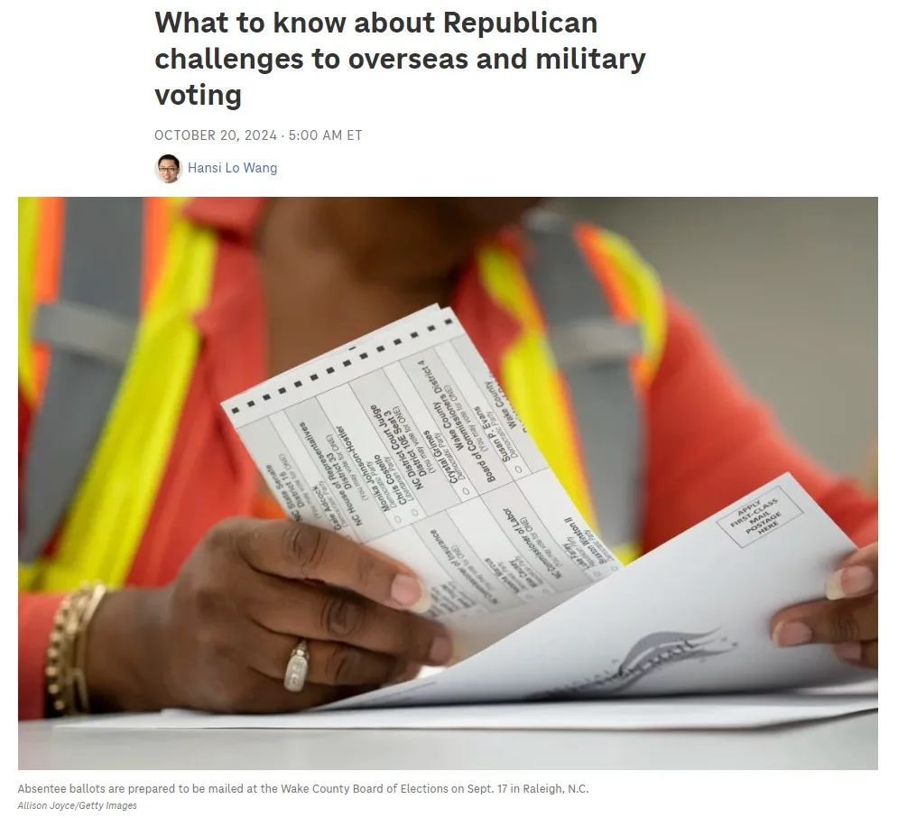 A person wearing a bright orange and yellow safety vest is holding and sorting through absentee ballots at a voting office…