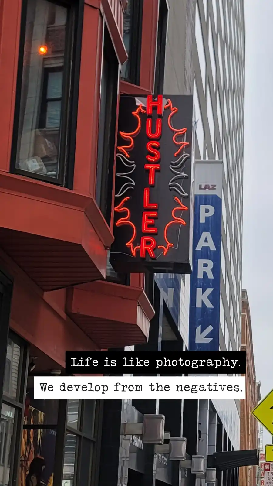 A photo of a red neon sign for 'HUSTLER' on a building, with a blue 'LAZ PARK' sign nearby. Overlaid text reads 'Life is…