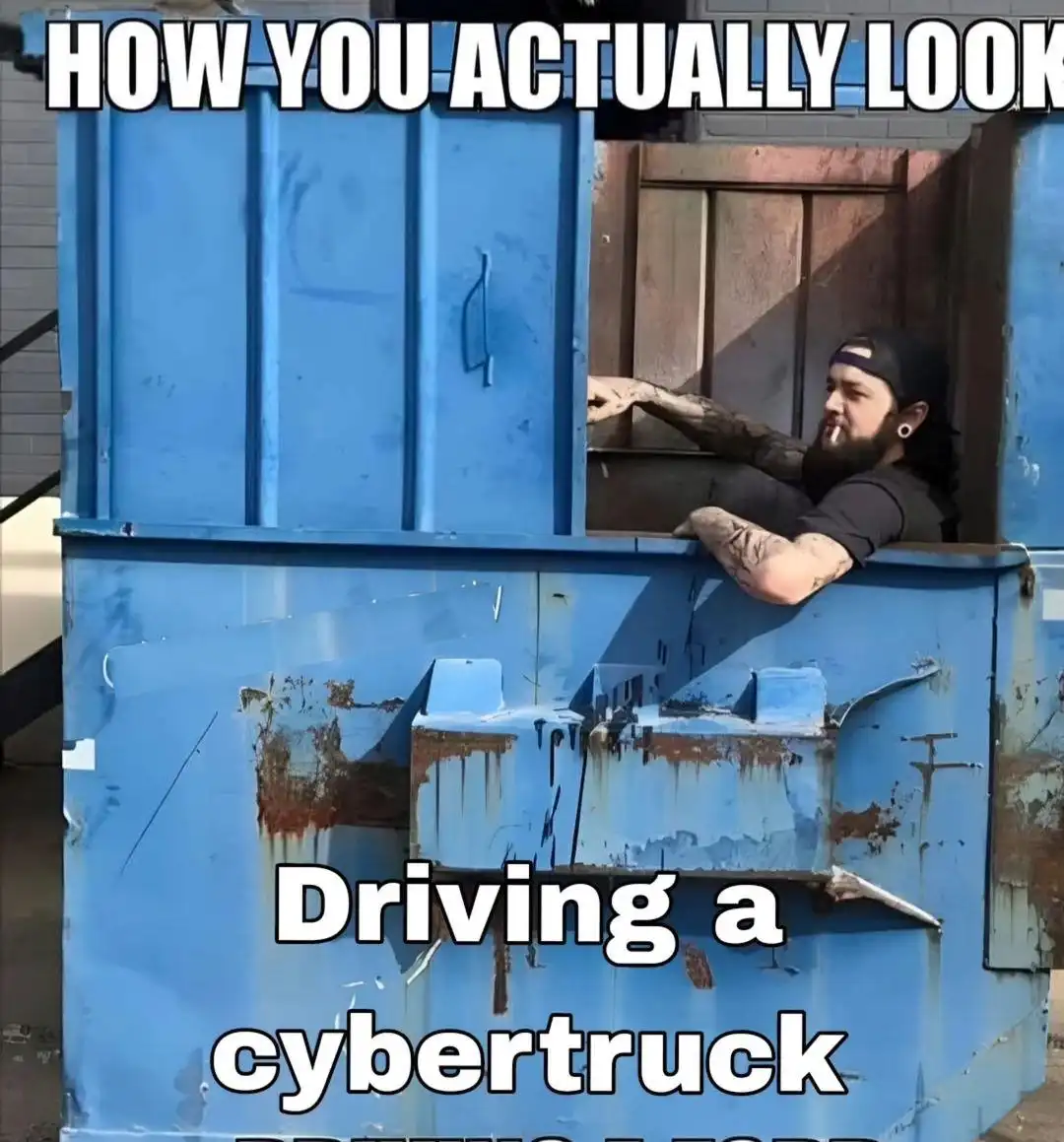 A man with tattoos and a beard, wearing a backward cap and ear gauges, leans out of a large, rusty blue dumpster. The text…