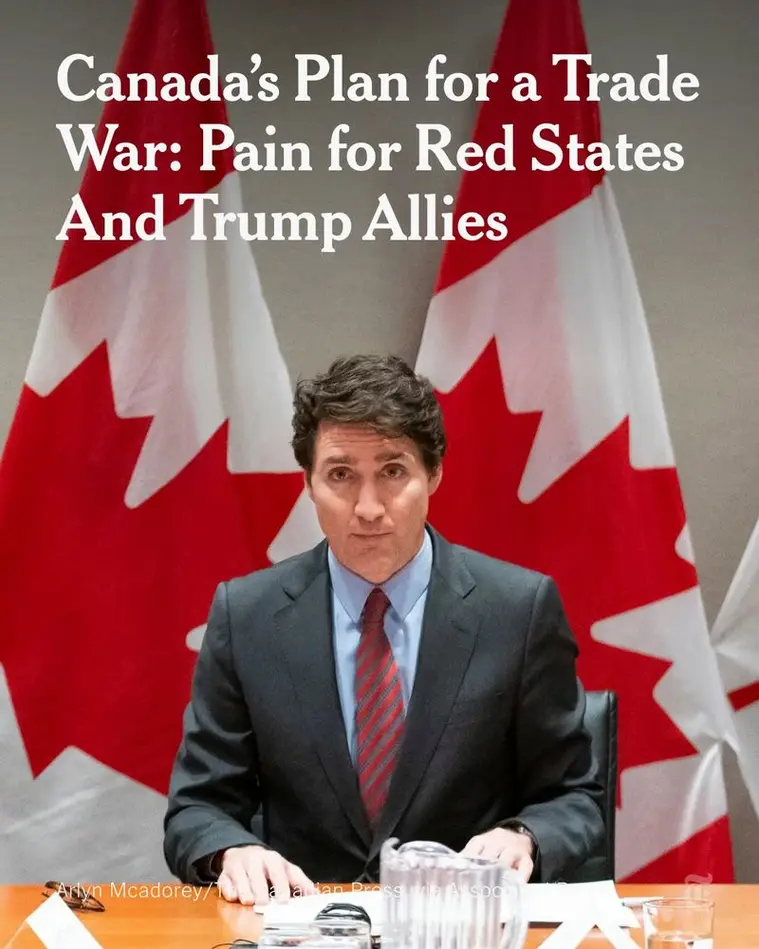 A man in a dark suit and red tie sits at a wooden table with two Canadian flags behind him. The overlaid white text reads…