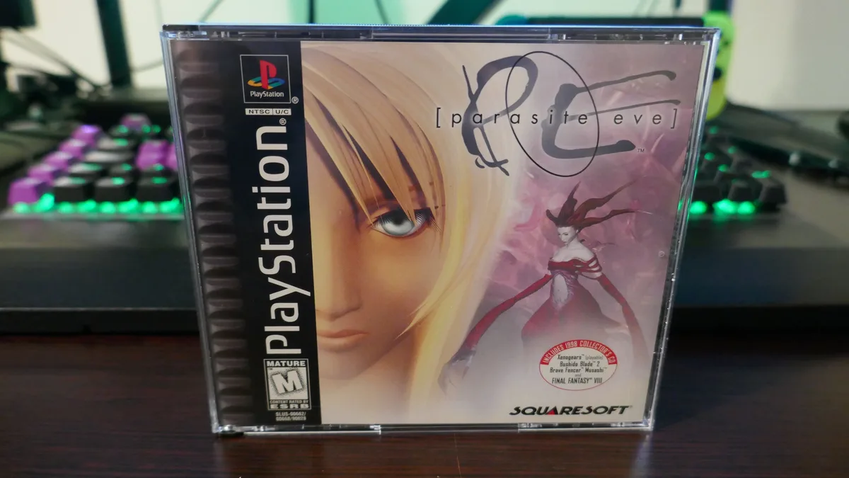 A physical PlayStation game case for 'Parasite Eve' by SquareSoft is shown standing upright on a desk, with a glowing…