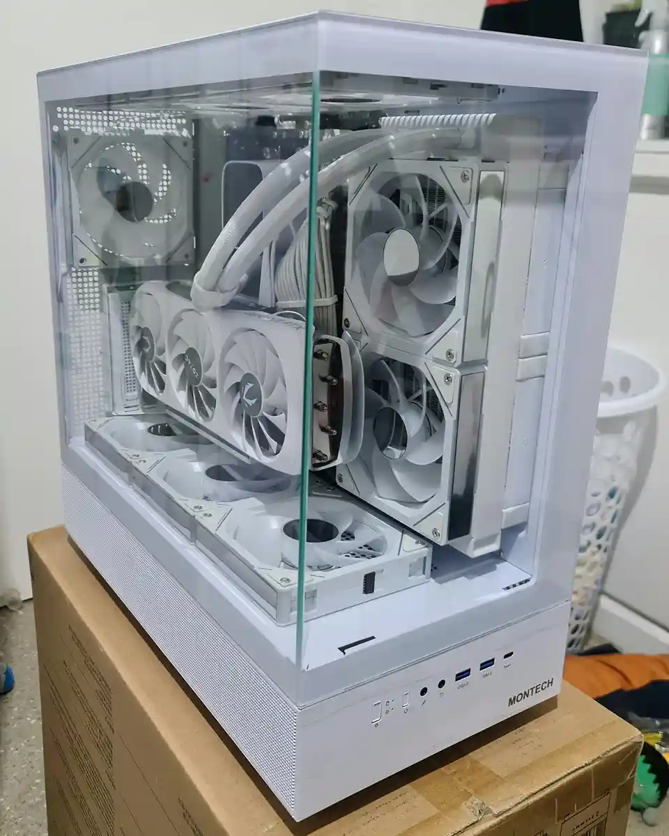 A white computer case with a clear side panel reveals an extreme cooling setup featuring at least ten white fans, including…