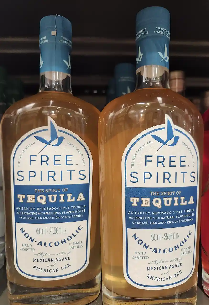Two identical bottles of 'Free Spirits' non-alcoholic tequila alternative sit side by side on a shelf, their labels clearly…