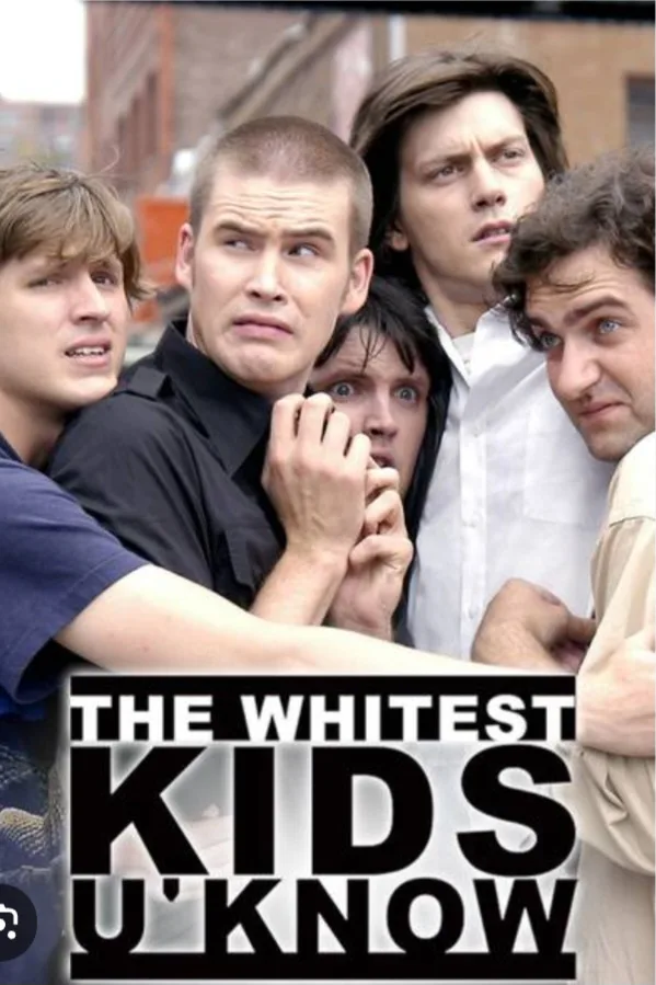 A group of five young men with varied expressions—some confused, some shocked, one with wide eyes—crowded together in an…