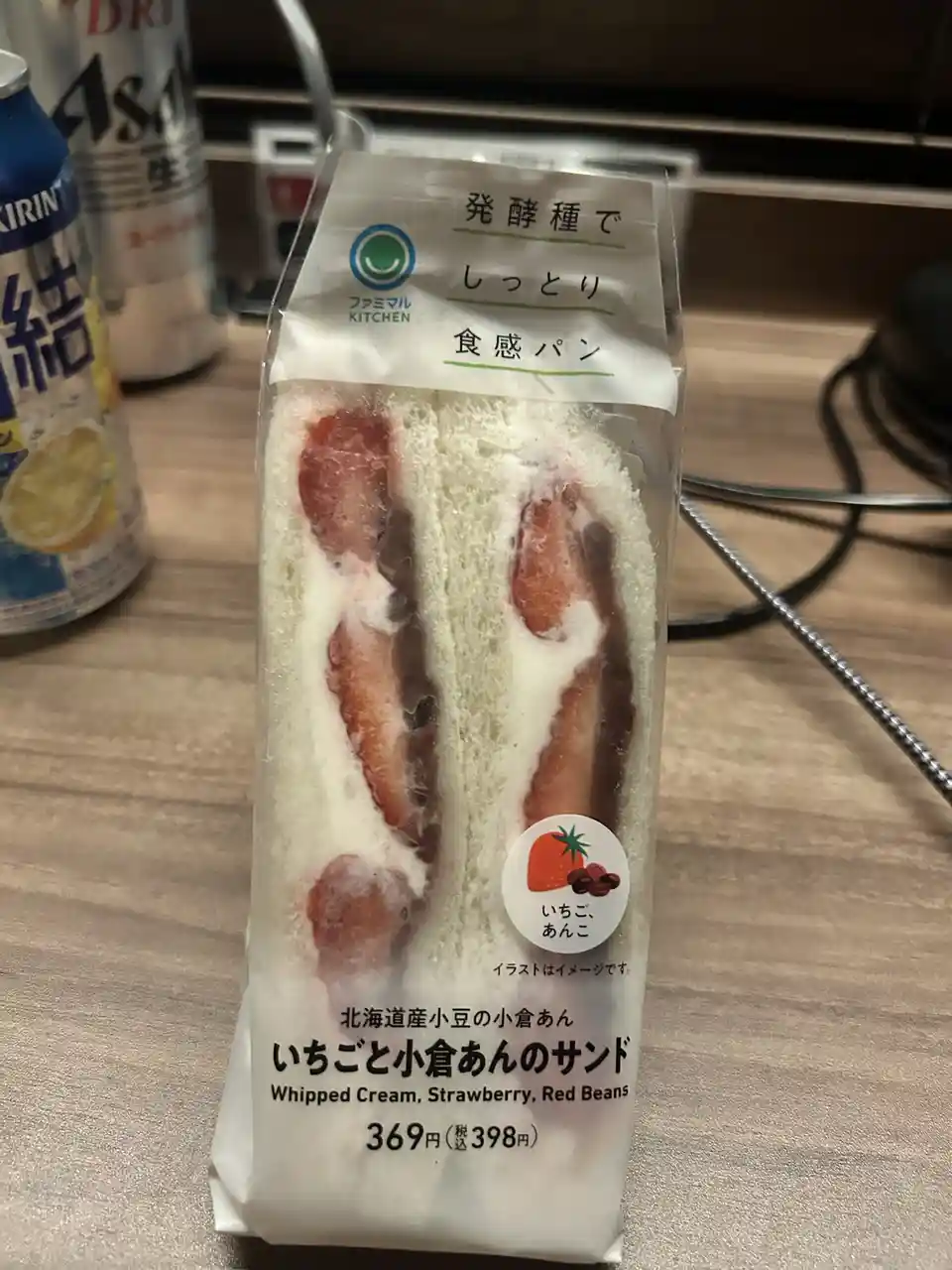 A packaged Japanese sandwich from Famima Kitchen, labeled 'Strawberry and Red Bean Sandwich' with whipped cream, strawberry…